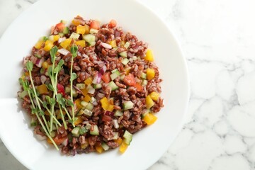 Tasty salad with brown rice on white marble table, top view