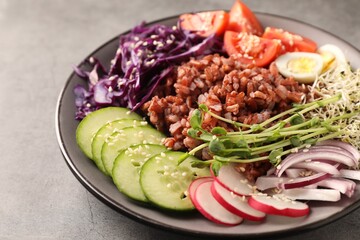 Tasty salad with brown rice on grey table, closeup