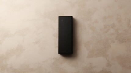 A minimalist black D-size battery mockup with subtle metallic accents on a taupe background