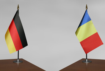 Table flags of Romania and Germany on a gray blurred background