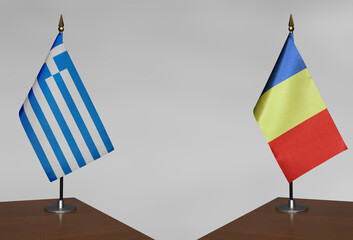 Table flags of Romania and Greece on a gray blurred background