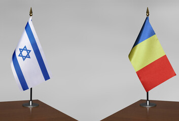 Table flags of Israel and Romania on grey blurred background