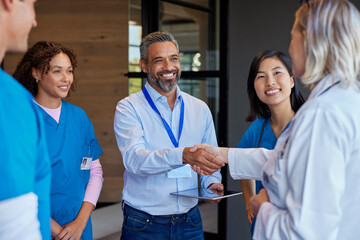 Mature woman doctor shaking hands with pharmaceutical representative at hospital