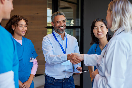 Mature woman doctor shaking hands with pharmaceutical representative at hospital - Powered by Adobe