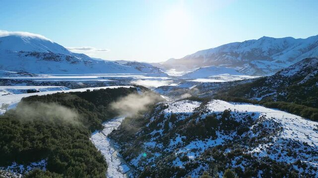 Drone shot tracking along a snowy creek, vally floor in New Zealands southern alps.