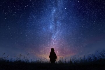 Silhouette of a figure gazing at a starry night sky filled with milky way.