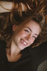 Close-up portrait of a happy young woman with freckles, smiling and looking at the camera.
