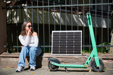 Woman using portable solar panel to charge electric scooter, emphasizing integration of sustainable...