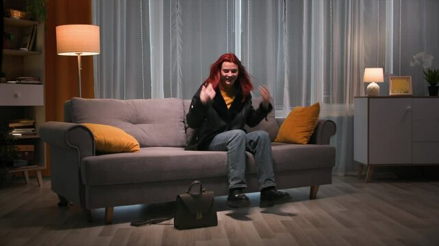 A beautiful woman in her outerwear and boots lyes to the sofa. Long shot. Slow motoin