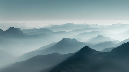Fototapeta premium Aerial view of misty mountains with soft blue and white sky hues, peaks standing out against foggy background, creating an ethereal natural landscape atmosphere.