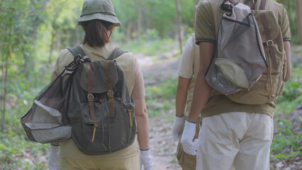 Rear view of an eco-conscious family hiking through the forest with reusable bags for litter collection, promoting sustainable trekking, zero waste practices, and environmental responsibility.