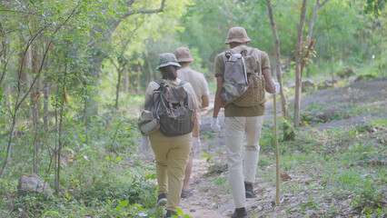 Naklejka premium Rear view of an eco-conscious family hiking through the forest with reusable bags for litter collection, promoting sustainable trekking, zero waste practices, and environmental responsibility.
