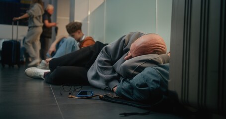 Crowded International Airport Terminal: Exhausted Man Sleeping on the Floor in Departure Lounge of...