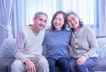 portrait bonding asian family enjoy leisure time in the living room together,sitting on sofa,embracing,smiling happily