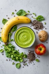 top view of a glass of healthy green smoothie surrounded by fresh ingredients like spinach, pea microgreens, banana, kiwi, apple