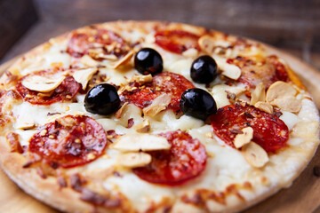 Pizza with salami and mozzarella cheese. Wooden background. Soft focus. Close up.	