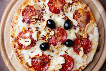 Pizza with salami and mozzarella cheese. Wooden background. Soft focus. Close up.	