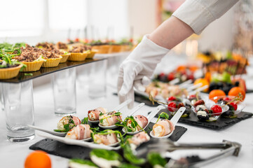 A gloved hand arranges an elegant assortment of gourmet appetizers on a table, including stuffed...