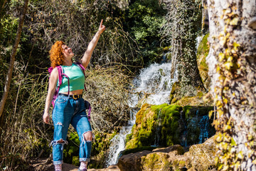 Fototapeta premium Tourist pointing at something while hiking near waterfall in the woods