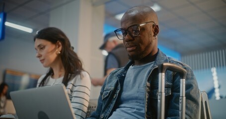 Crowded International Airport Terminal: African American Man Working on Laptop, Having Online Video...