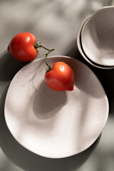 Flat lay of gray monochrome plates and tomatoes. Culinary concept with space for text
