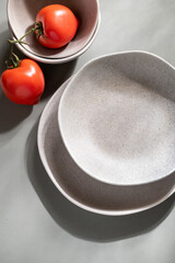 Flat lay of gray monochrome plates and tomatoes. Culinary concept with space for text
