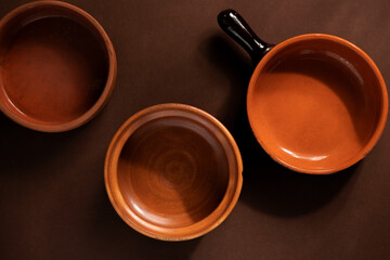 Arrangement of ceramic plates on brown background. Earthenware pottery objects, space for text. 
