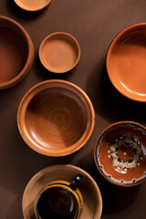 Arrangement of ceramic plates on brown background. Earthenware pottery objects, space for text. 
