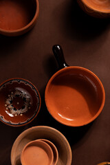 Arrangement of ceramic plates on brown background. Earthenware pottery objects, space for text. 
