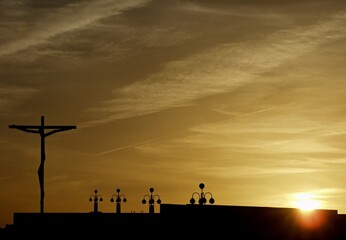 A large crucifix stands on the rooftop at sunset with a cloudy sky in Fatima, Portugal