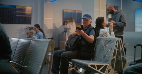 Obraz premium Crowded International Airport Terminal: African American Young Man Sitting, Waiting for Airplane Flight, Going on Vacation Trip. Multiethnic People and Passengers in Departure Lounge of Airline Hub.