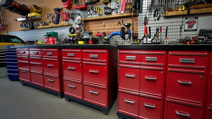 Red metal tool cabinets in a well-lit workshop, other tools and vehicles visible in the background - Powered by Adobe