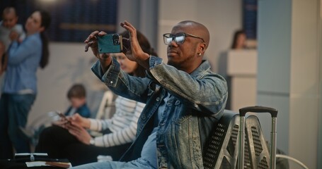 Crowded International Airport Terminal: African American Travel Blogger Filming Video Content from Vacation Trip Using Smartphone. Diverse People Waiting for Flight in Departure Lounge of Airline Hub.