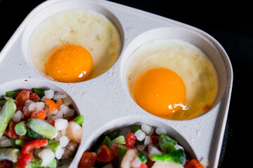 Two eggs sunny side up with mixed frozen vegetables in cooking tray