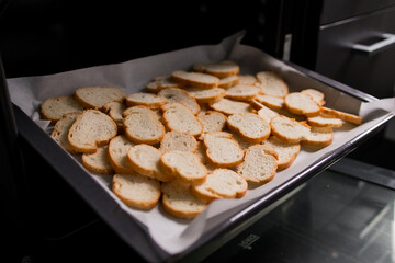 Sliced bread baking in oven with golden toasted crust on tray