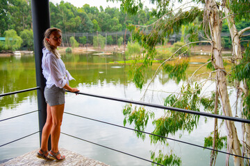 One girl is standing by the lake in the arboretum