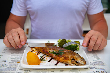 Man eating fried trout in a restaurant