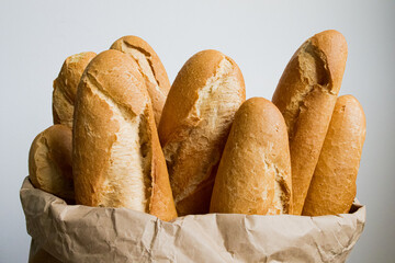Freshly baked baguettes overflowing from a brown paper bag