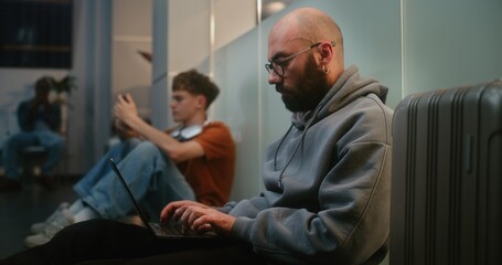 Crowded International Airport Terminal: Man Working Online on Laptop, Sending e-Commerce Emails,...