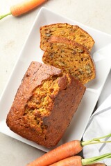 Homemade carrot cake with nuts and vegetables on light grey table, flat lay