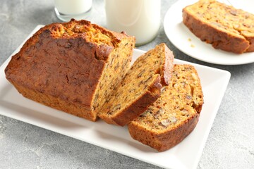 Cut homemade carrot cake with nuts and milk on grey table, closeup