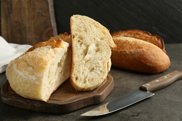 Different types of fresh bread and knife on dark textured table, closeup