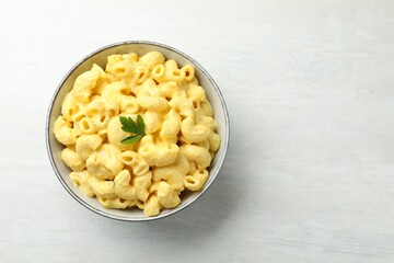 Delicious pasta with cheese sauce in bowl on light table, top view. Space for text