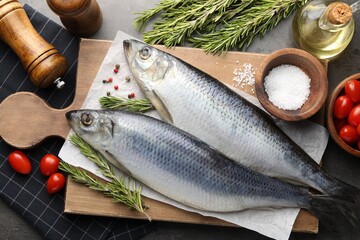 Salted herrings, spices and tomatoes on grey table, flat lay