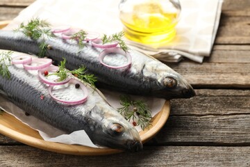 Tasty herrings with spices on wooden table, closeup