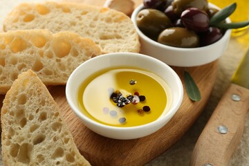Slices of bread with oil, spices and olives on light table, closeup