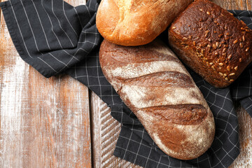 Different types of fresh bread on wooden table, flat lay. Space for text