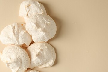 Delicious homemade meringue cookies on beige background, top view. Space for text