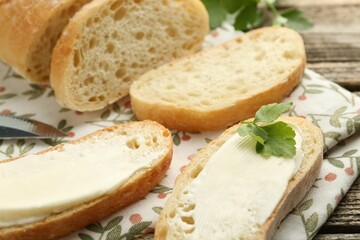 Pieces of bread with butter and parsley on wooden table, closeup