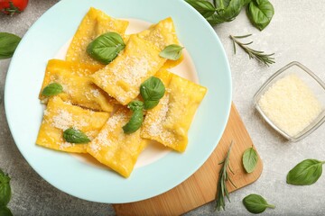 Delicious ravioli with cheese and basil served on grey table, flat lay